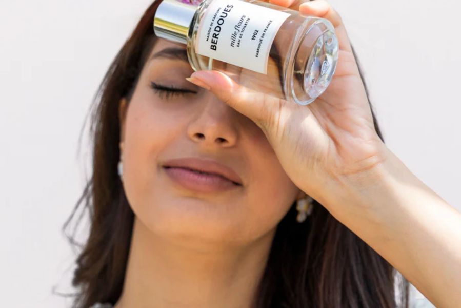 Femme appliquant une fragrance légère Berdoues en extérieur illustrant le choix d’un parfum frais et lumineux adapté à la saison estivale